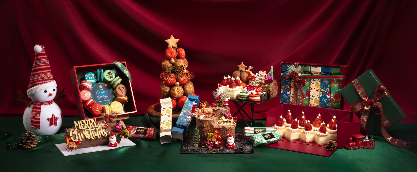 Christmas display with a snowman figure, profiterole tree and gift boxes on a red backdrop — Elevete Patisserie