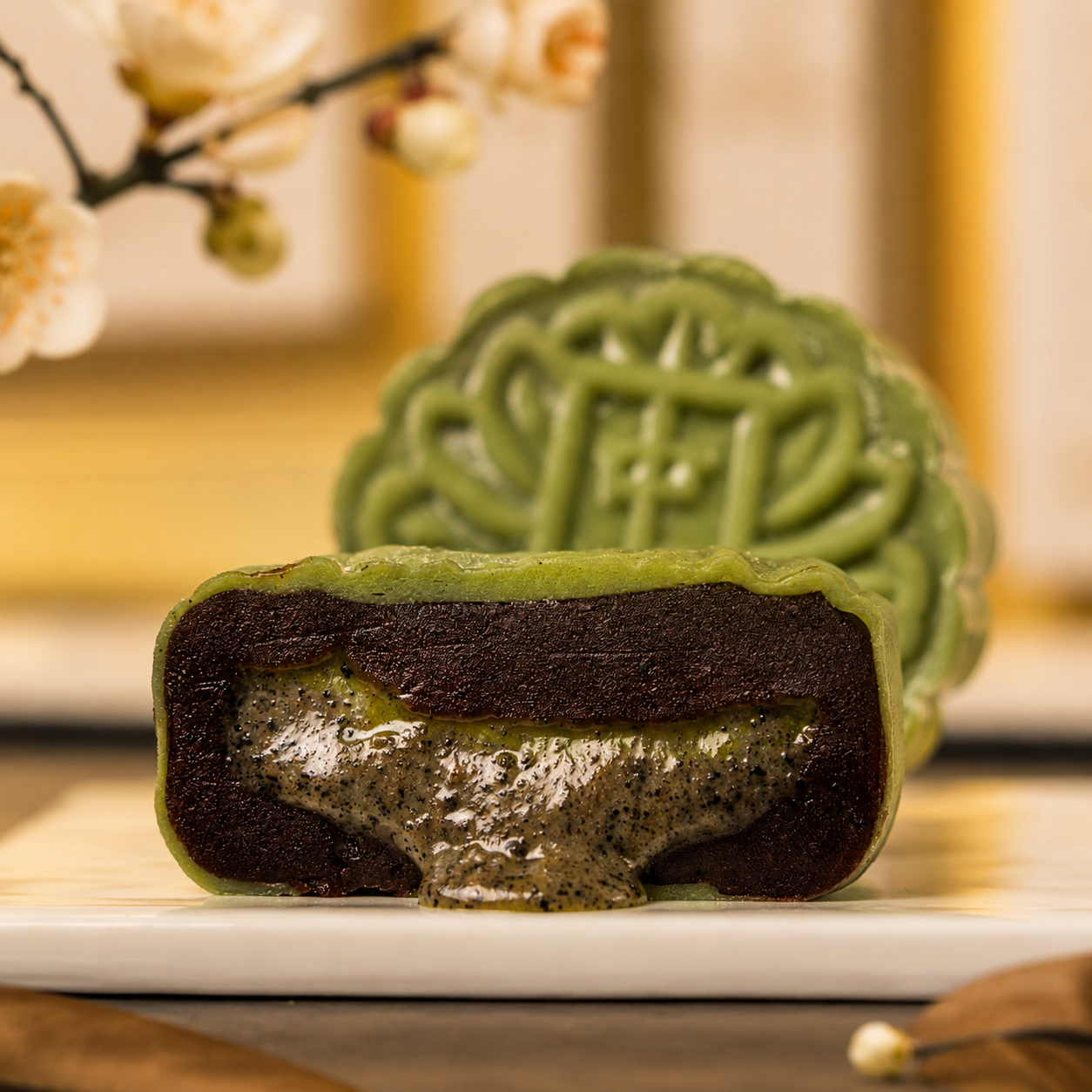 Matcha snowskin mooncake cut open, showing the black sesame layer beneath the green skin — Elevete Patisserie KL