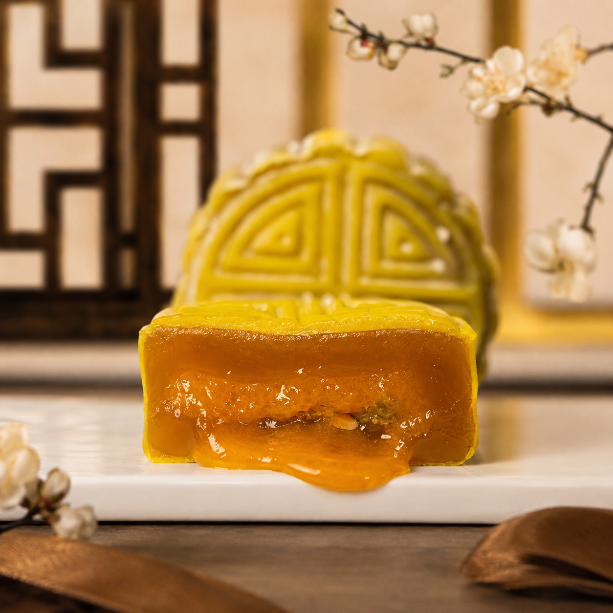 Salted egg yolk snowskin mooncake cut open, molten yolk running out over lotus paste — Elevete Patisserie KL