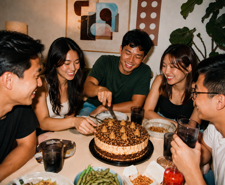Group of friends celebrating a birthday and cutting a Tiramisu cake from Elevete Patisserie together at a dinner gathering